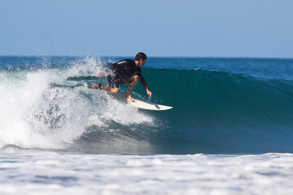 Surfeur professionnel réalisant une manœuvre, illustrant un article pour débuter et progresser en surf