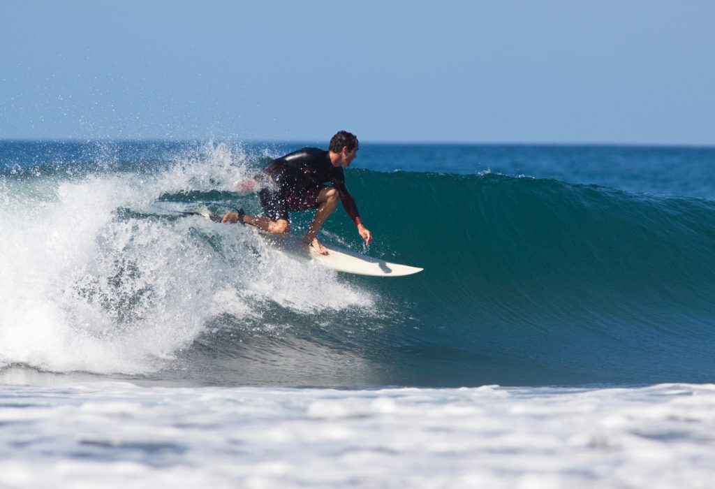 Surfeur professionnel réalisant une manœuvre, illustrant un article pour débuter et progresser en surf